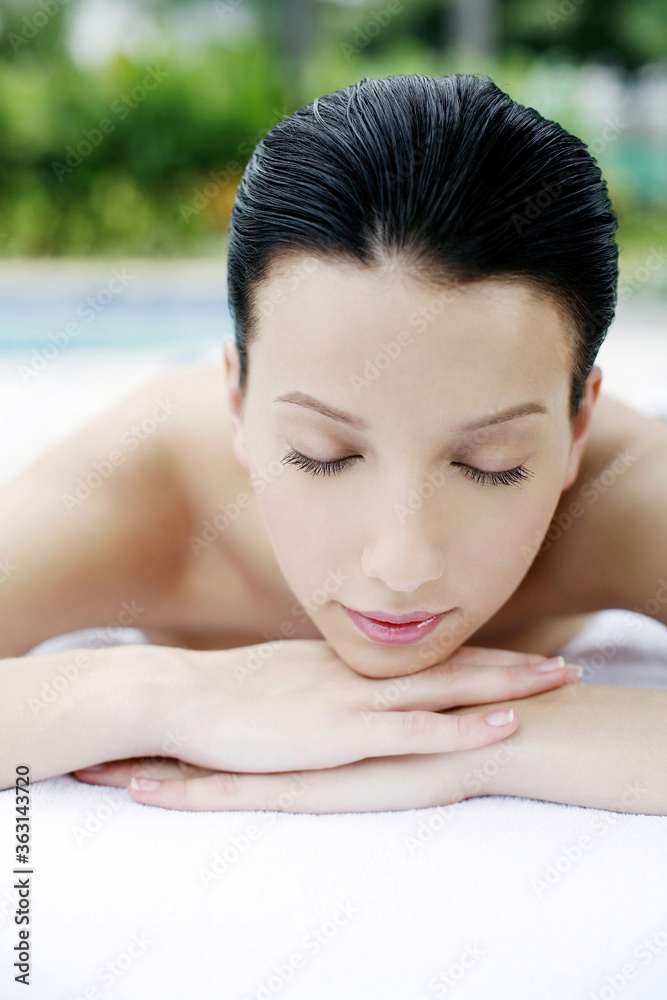 Woman lying forward on massage table with her eyes closed Woman lying forward on massage table with her eyes closed