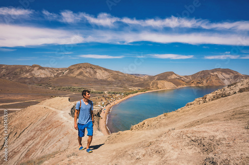 Man climbing mountain above blue lagoon landscape.