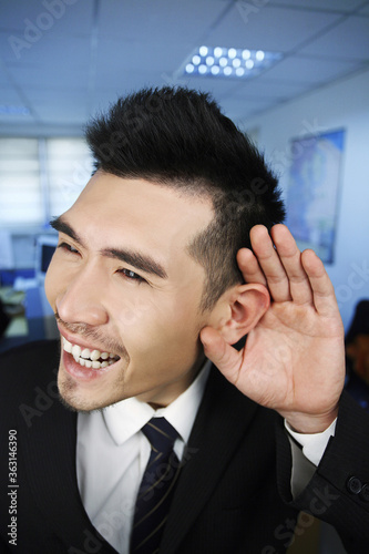 Businessman with cupped hand on ear
