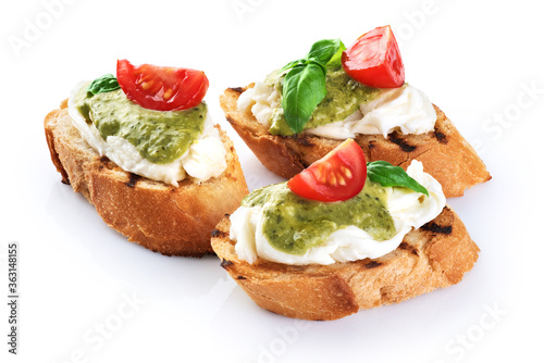 Bruschetta with mozzarella cheese, pesto, tomatoes and basil isolated on white background.