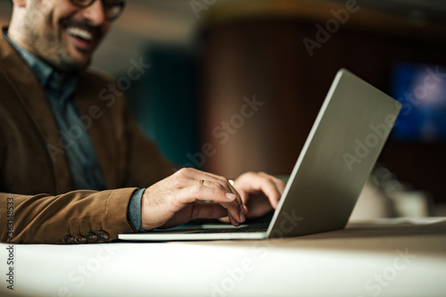 Smiling businessman working on laptop, close-up, copy space.