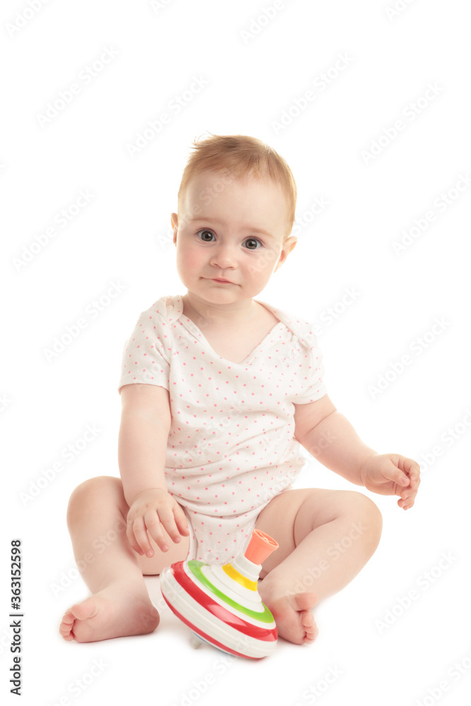 Cute baby girl sitting and playing with a toy isolated on white background Cute baby girl sitting and playing with a toy isolated on white background