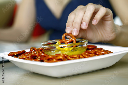 Woman dipping mini pretzel into honey mustard dip