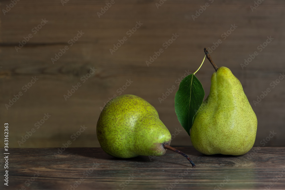 two ripe juicy pears Williams with green leaves on a wooden table