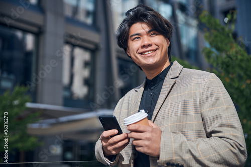 Joyful young man using mobile phone outdoors