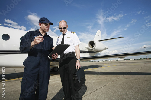 Plane engineer and pilot looking at document on clipboard