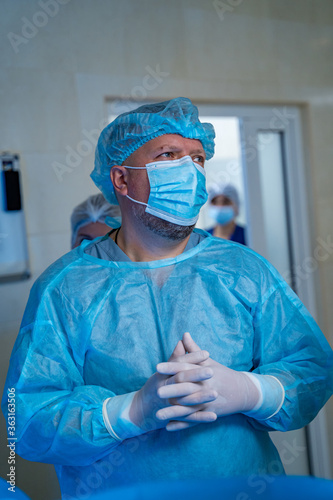 Doctor in scrubs. Clinic interior. Surgeon wearing mask, gloves and medicine hat. Medicine concept