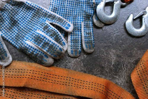 top view of dirty gloves and car tow rope on wooden surface
