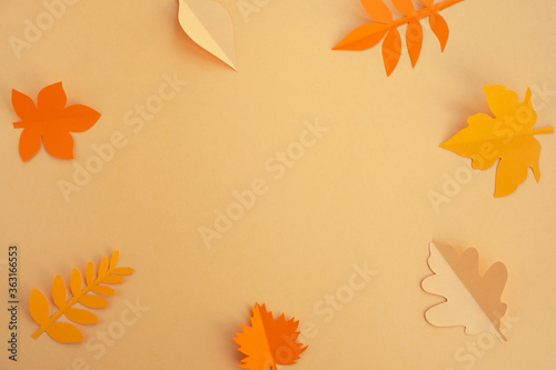 Autumn leaves made from paper on orange background. Greeting card, fall season concept. Top view, flat lay, copy space, frame