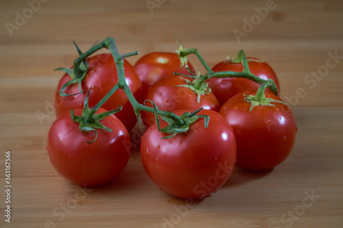 Branch of ripe red tomatoes on a wooden surface