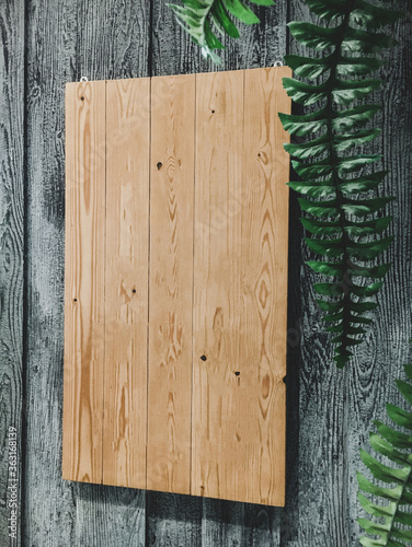 Wooden plan that hangs on the wall With green leaves on the side