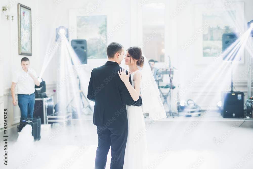 Naklejka premium First wedding dance of newlywed couple in restaurant