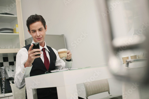 Businessman text messaging on the phone during tea break