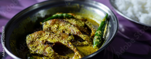 hilsa fish curry with mustard paste and green chilli served on plate along side rice with selective focus photo