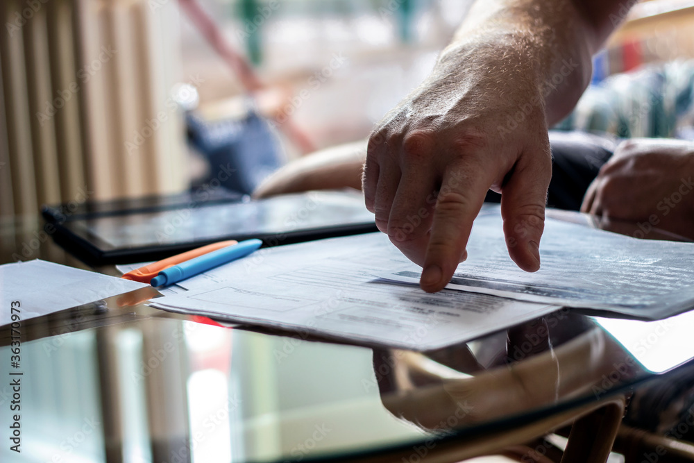 Image of male hand pointing at business document.Businessman discussing the charts and graphs showing the results of their successful teamwork.Close-up of male hands pointing at document.