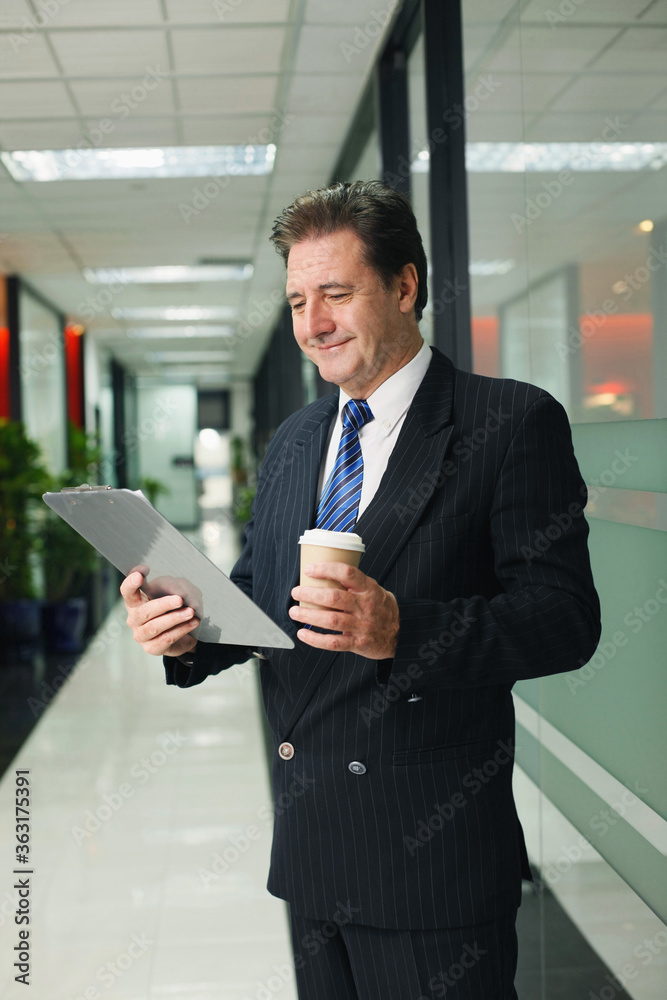 Businessman holding clipboard and a cup of coffee