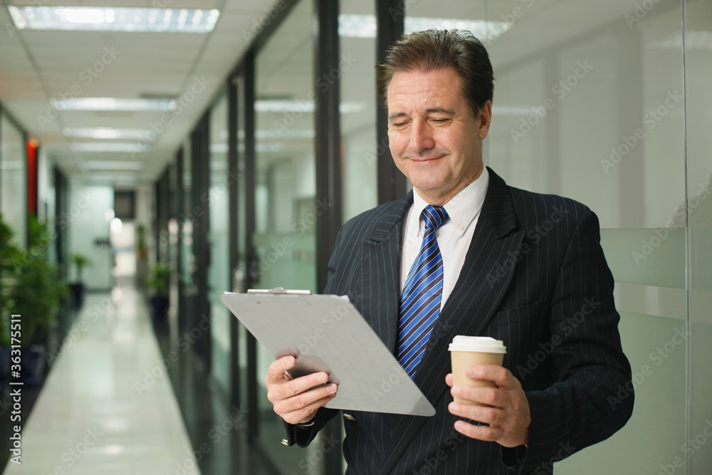 Businessman holding clipboard and a cup of coffee Businessman holding clipboard and a cup of coffee