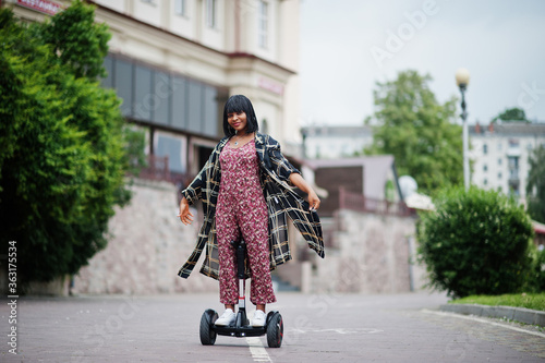 Beautiful african american woman using segway or hoverboard. Black girl on dual wheel self balancing electrical scooter. photo