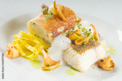 Baked zander fillet on a plate. Delicious fish meal - walleye fillet with mushrooms and served with tagliatelle. Studio shot.