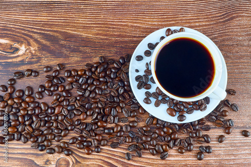 Coffee cup and coffee beans on old wooden background. Top view with copyspace for your text.