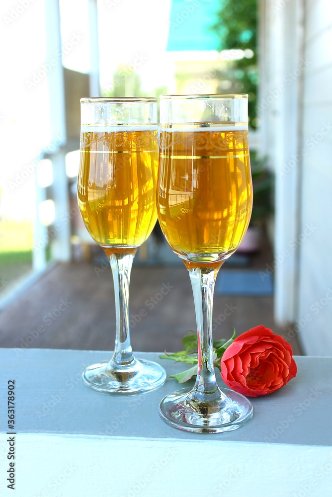 On the summer terrace, two glasses of drink, a rose. Rest and romance. On the summer terrace, two glasses of drink, a rose. Rest and romance.
