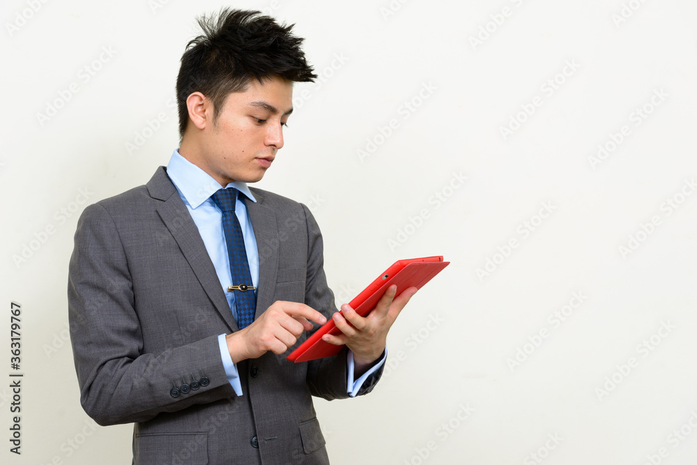 Portrait of young handsome Asian businessman in suit using digital tablet Portrait of young handsome Asian businessman in suit using digital tablet