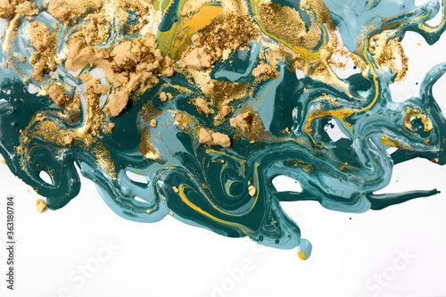 Gold and blue mixed inks splattered on white paper background. © anya babii