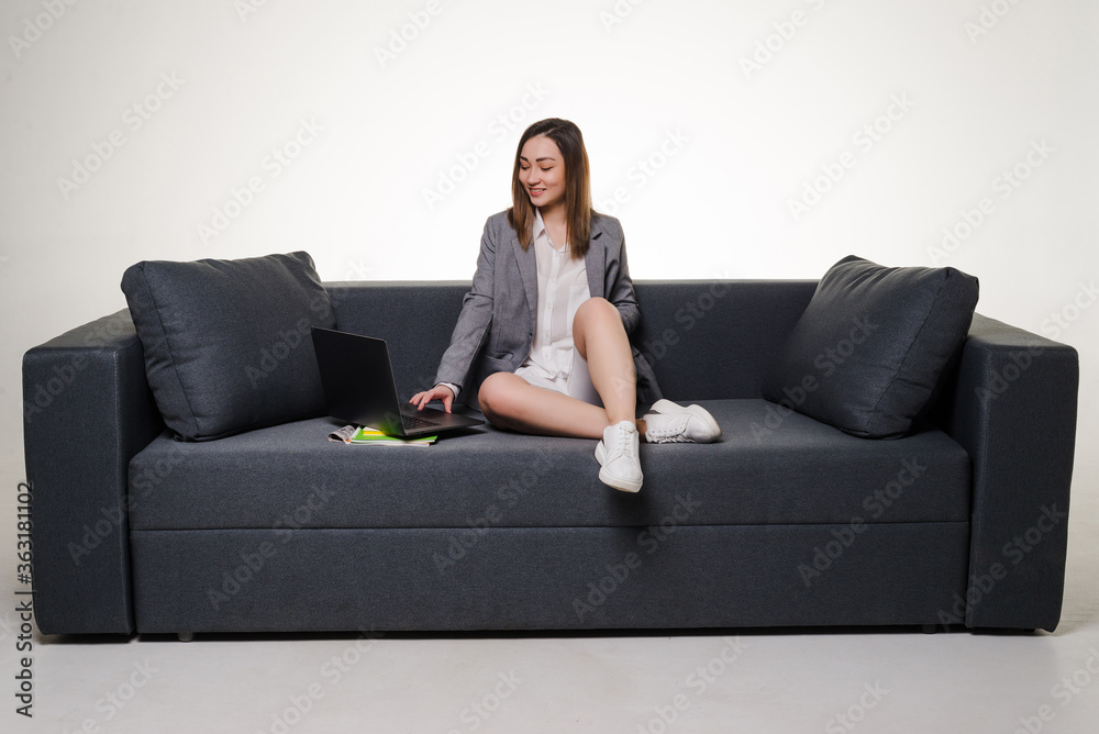 Young woman lying on sofa at home working on laptop computer isolated on white background. Young woman lying on sofa at home working on laptop computer isolated on white background.