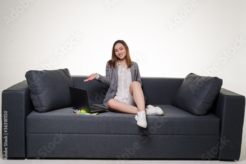 Young woman lying on sofa at home working on laptop computer isolated on white background.