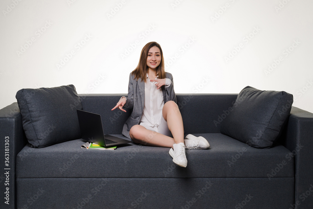 Obraz premium Young pretty woman pointed on laptop lying on the sofa isolated on white background