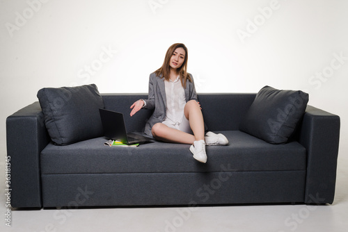 Young pretty woman pointed on laptop lying on the sofa isolated on white background