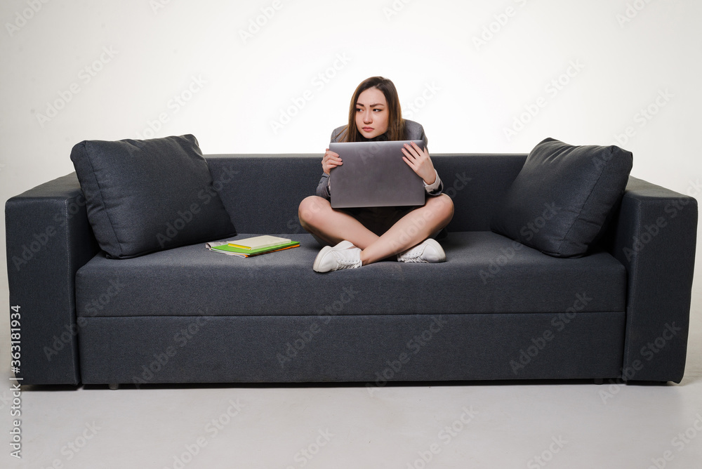 Young asian woman worried working on laptop sitting on sofa isolated on white background Young asian woman worried working on laptop sitting on sofa isolated on white background