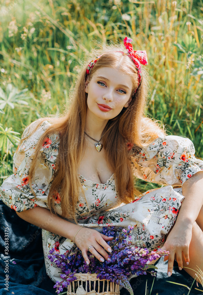 Naklejka premium Lovely cute woman in lupine field, sunny day, freedom concept
