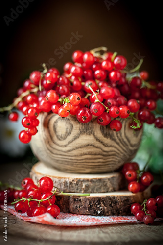 Fresh red currants in plate on dark rustic wooden table. Background with copy space. Selective focus.