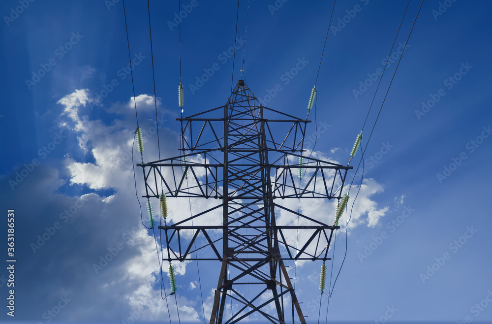 Power line pylon against a bright blue sky. Power transmission tower against the blue sky background. Power line pylon against a bright blue sky. Power transmission tower against the blue sky background.