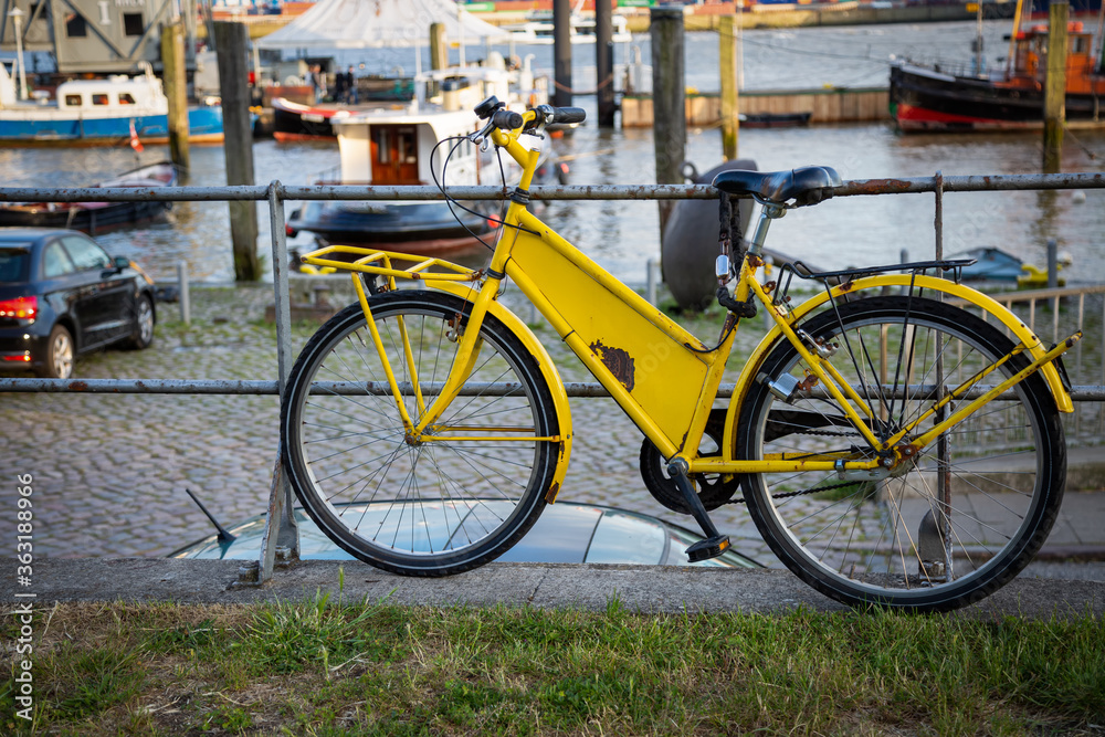 Gelbes Fahrrad an einem Geländer im Hafen