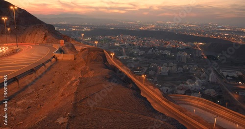 Sunset time lapse with turning roads and cars moving in an orange glow over Muscat, Oman.