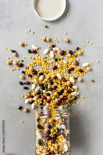Verschiedene Hülsenfrüchte in einem Einmachglas auf einem grauen Hintergrund verstreut. Flat lay, pflanzliches Protein. photo