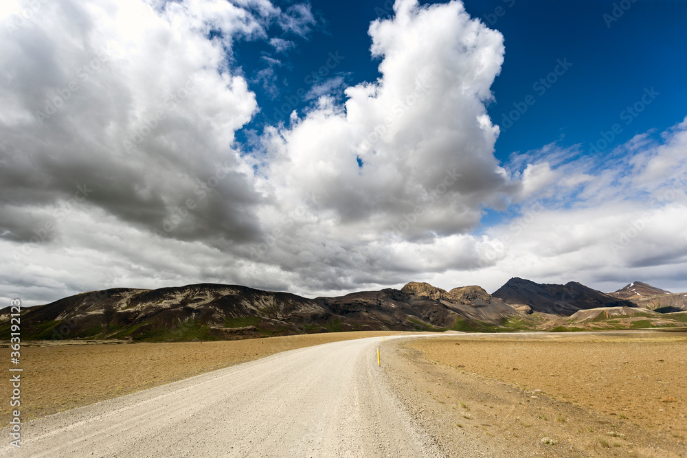 Landscape of a dirt road with stunning clouds in the background
