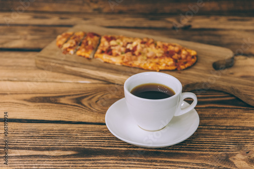 Little pizza on a wooden table with a cup of coffee. Fast food cooked at home.