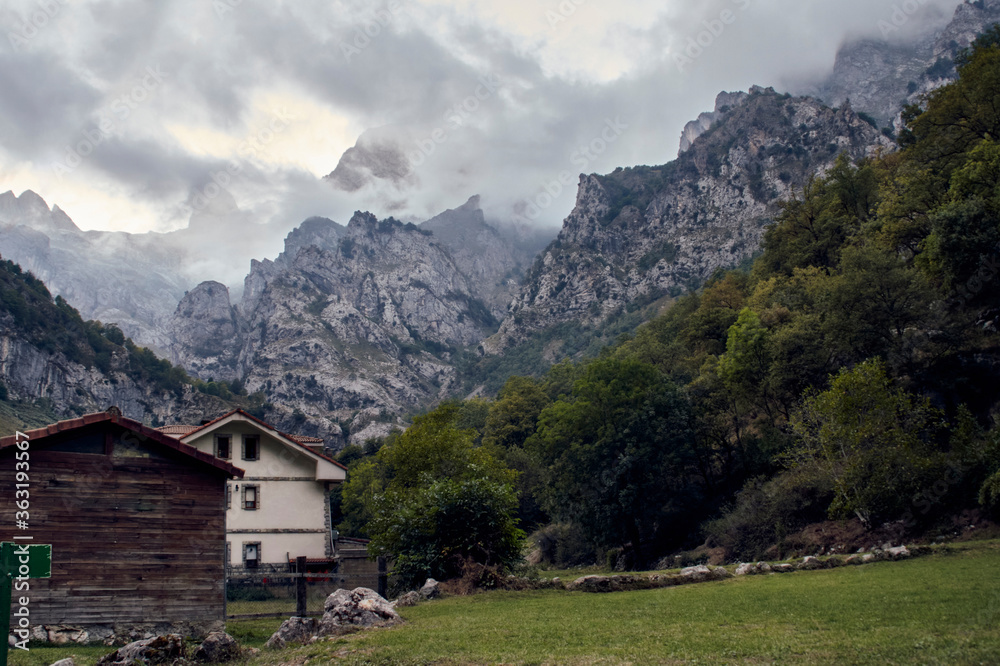 Little Houses in front of mountains whit dramatic clouds.
