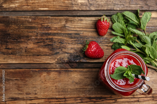 Tasty strawberry smoothie with mint in mason jar on wooden table, flat lay. Space for text