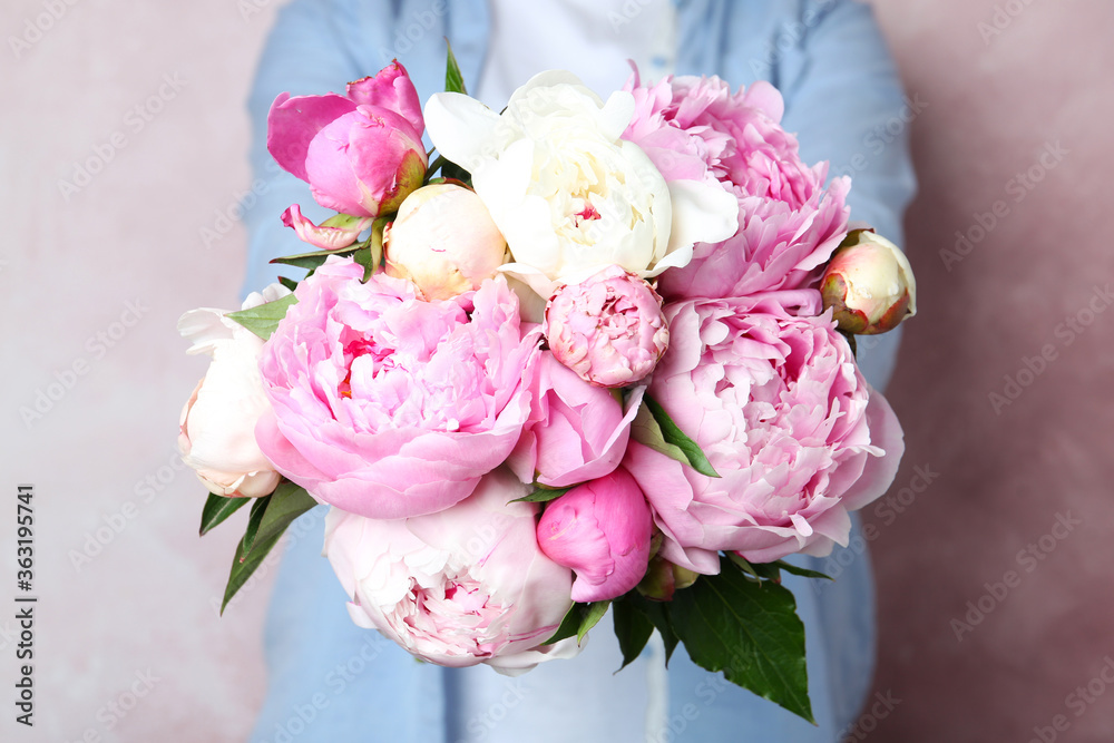 Woman with bouquet of beautiful peonies on pink background, closeup