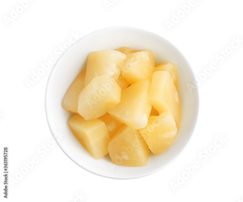 Pieces of delicious canned pineapple in bowl on white background, top view