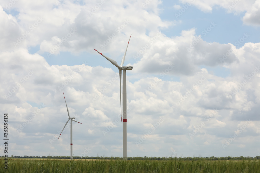 Modern wind turbines in field on cloudy day. Alternative energy source Modern wind turbines in field on cloudy day. Alternative energy source