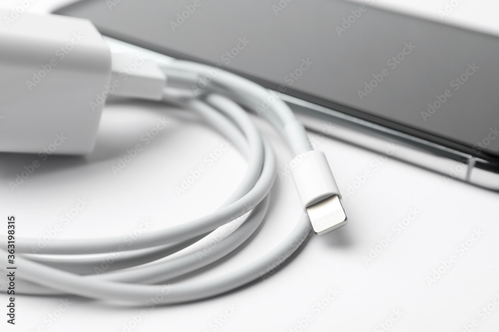 Smartphone and charging cable with adapter on white background, closeup Smartphone and charging cable with adapter on white background, closeup
