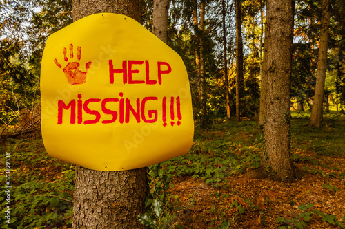 a sign reading help missing /a woman after hanging a sign on a tree to ask for help, wandering disoriented in the woods