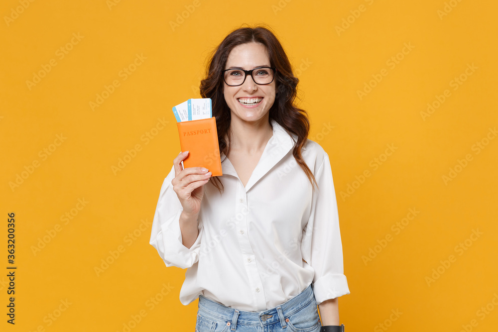 Smiling young brunette business woman in white shirt glasses isolated on yellow background studio. Achievement career wealth business concept. Mock up copy space. Hold passport tickets boarding pass. Smiling young brunette business woman in white shirt glasses isolated on yellow background studio. Achievement career wealth business concept. Mock up copy space. Hold passport tickets boarding pass.