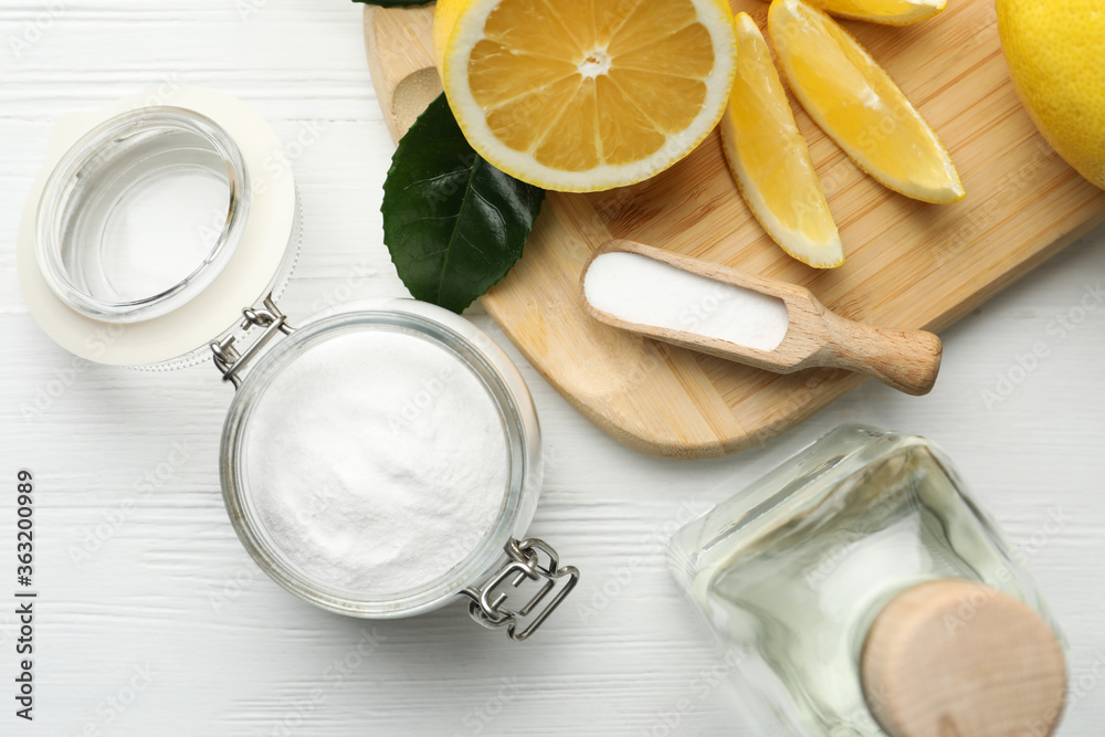 Baking soda, vinegar and cut lemons on white wooden table, flat lay Baking soda, vinegar and cut lemons on white wooden table, flat lay
