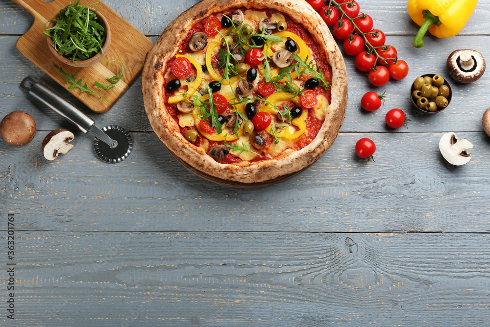 Flat lay composition with vegetable pizza on light grey wooden table. Space for text
